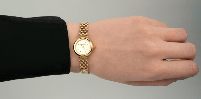 жіночий золотий годинник на руці
