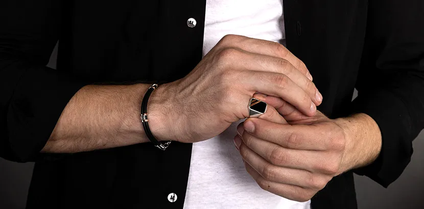 Каучуковий браслет зі вставками із золота і печатка на чоловічій руці.